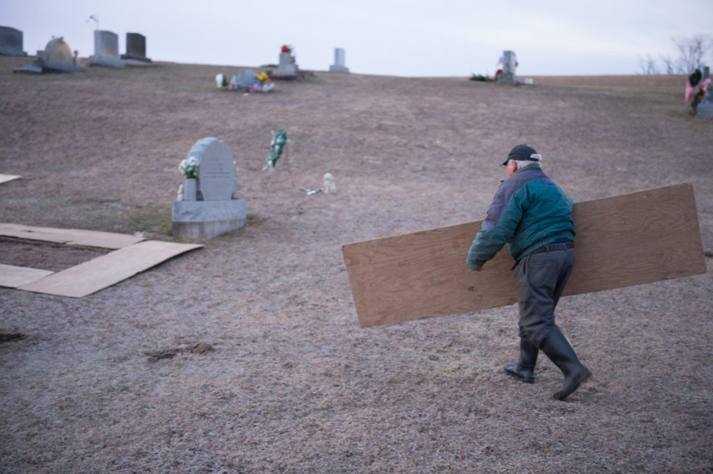 Bibbee puts supplies in place before beginning to dig. Rather than work with the aid of machinery, Bibbee prefers to do all his work manually, even at the age of 82. The mark of a veteran gravedigger.