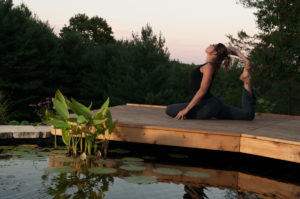 Liz Chamberlain, owner of the Bodhi Tree Guesthouse and Studio, is doing a one legged king pigeon pose on the reflection pond's deck.