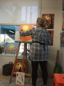 Owner, Bobbi McKinnon, leads a group painting session in painting a Fall themed canvas.